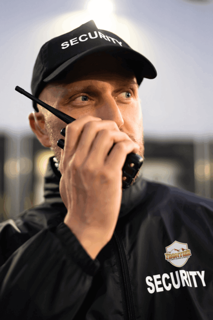 Frontier Security guard in uniform using a radio to communicate while on duty, representing professional local security services for Denver businesses.