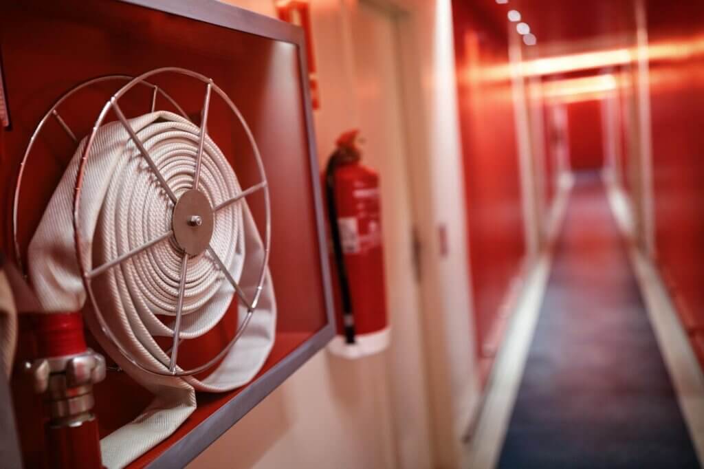 Fire extinguisher and hose reel in a hotel-style corridor used for fire watch safety in a Denver commercial building
