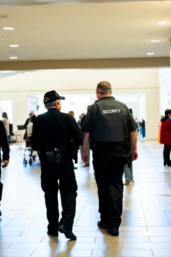 Two uniformed security guards walking through an indoor mall common area