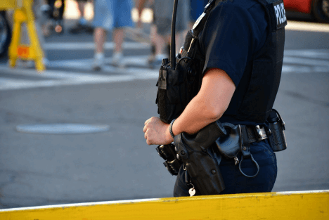 A police officer monitors an outdoor event area from behind a barricade to support public safety.