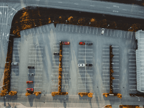 Aerial view of mostly empty parking lots near commercial buildings, highlighting after-hours perimeter exposure.